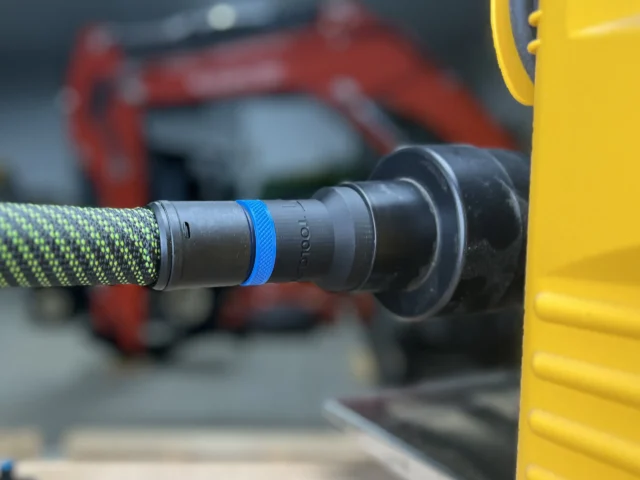 Black hose adapter with blue band attached to green and black Festool hose, connected to Dewalt 734 planer dust port