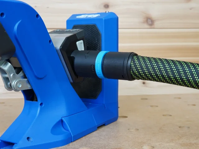 Blue hose adapter attached to Kreg 720 pocket-hole jig with black dust collection port and bright green braided hose connected