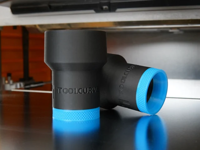 Black hose adapter with blue grip band, ToolCurve branding visible, shown as two units on a work surface