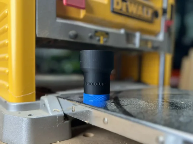 Black ToolCurve hose adapter with blue band, mounted on a Dewalt 734 planer dust port