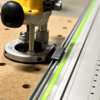 Dewalt DW618 plunge router mounted on a Festool-style guide rail via adapter, showing the black plunge knob and baseplate aligned with the rail's holes