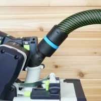 Black hose adapter with blue band attached to Festool sander dust port, green fabric hose connected above