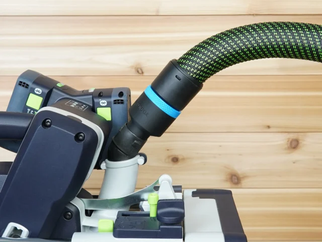 Black hose adapter with blue band attached to Festool sander dust port, green fabric hose connected above