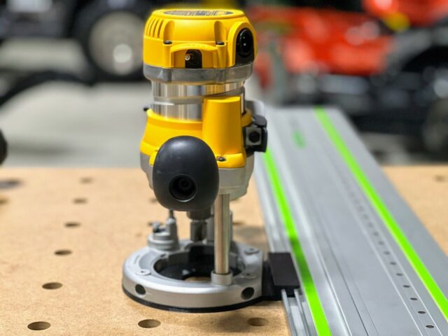 DeWalt DW618 plunge router mounted on a Festool guide rail adapter, seated on a wooden board with alignment holes