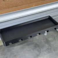 Black tray mounted in a Festool MFT/3 workbench t-track, with notched slots along the side for holding clamps and a flat storage area