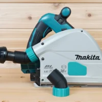 ToolCurve No-Snag Dust Port Adapter installed on a Makita track saw, angling the orange and black vacuum hose upward away from the cutting area
