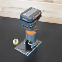 Clear acrylic extended base plate mounted on a Ridgid trim router, with a brass collet shown separately for size reference