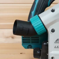 Turquoise twist-lock hose adapter connected to black dust port on Makita track saw, angled upward away from the cut area
