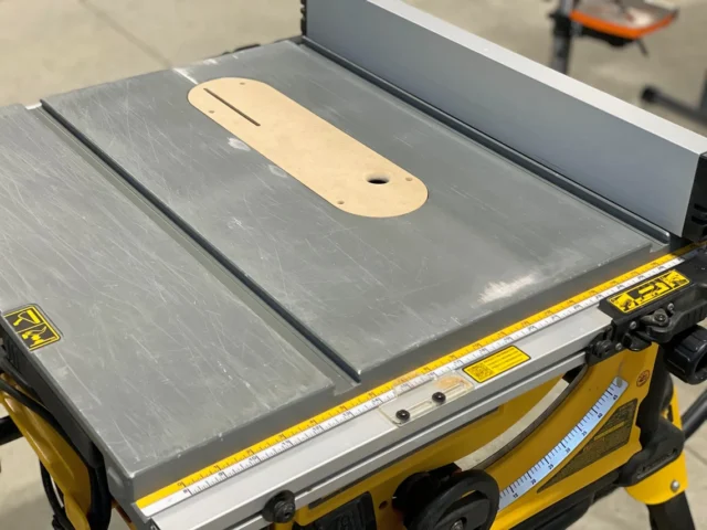 Wooden zero clearance insert with offset screw holes installed on Dewalt table saw blade throat