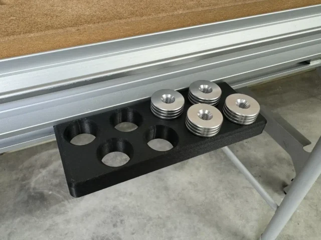 Black PLA Plus MFT bench dog holder in the workbench t-track, four metal dogs in eight round slots