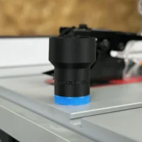 Black hose adapter with blue grip band sitting on a SawStop table saw dust port, ToolCurve branding visible