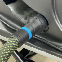 Black hose adapter with blue collar attached to SawStop table saw dust port, connected to yellow-and-black braided hose