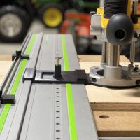 Dewalt DW618 router mounted on LR32 rail system with plunge base adapter and hole drilling jig installed on wooden workbench
