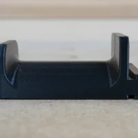 Black 3D-printed holder with curved side grips, designed to slide into a Festool MFT/3 table t-track slot