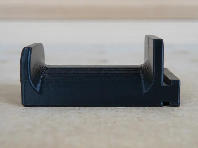 Black 3D-printed holder with curved side grips, designed to slide into a Festool MFT/3 table t-track slot