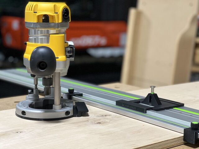 DeWalt DW618 plunge router mounted on LR 32 rail with black adapter plate and spring-loaded knob, positioned on Festool track
