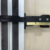Black narrow rip guide attached to aluminum track rail with two screw holes and mounting tabs visible