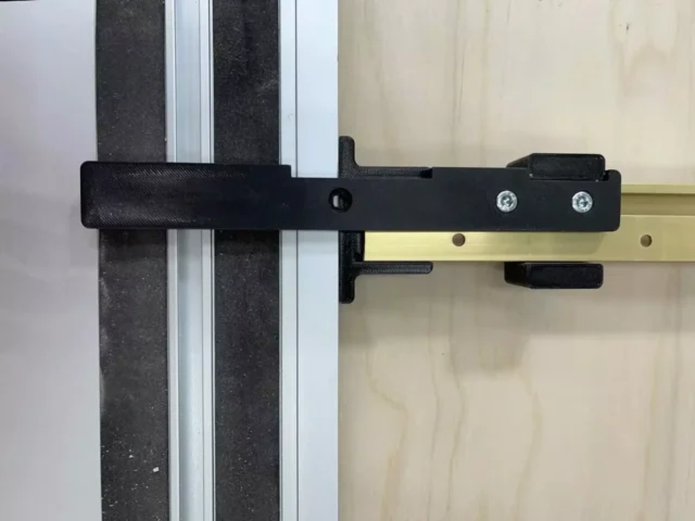 Black narrow rip guide attached to aluminum track rail with two screw holes and mounting tabs visible