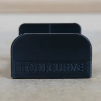 Black plastic headphone holder with ToolCurve branding, designed to slide into MFT/3 table t-track slot