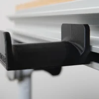 Black plastic headphone holder mounted on Festool MFT/3 table t-track with padded top and sides, shown from the side angle