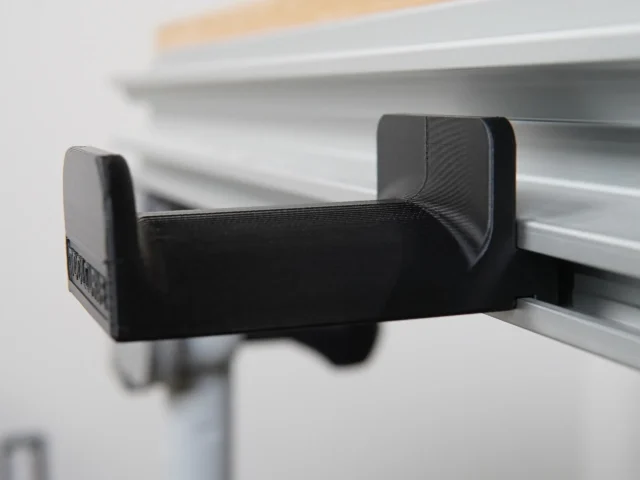 Black plastic headphone holder mounted on Festool MFT/3 table t-track with padded top and sides, shown from the side angle