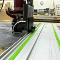 ZetaRail connector mounted on Festool guide rail with green edge straps, positioned on Lamello Zeta domino jointer in workshop