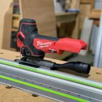 Milwaukee M18 jig saw with ToolCurve rail adapter mounted on a Festool track rail with green stripe
