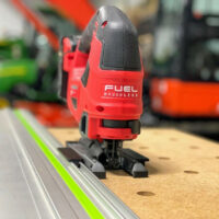 Milwaukee M18 jig saw with red FUEL body mounted on a green Festool rail via a snap-on adapter plate, showing the base connector