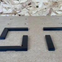 Four black corner and straight fence segments arranged on a perforated workbench surface