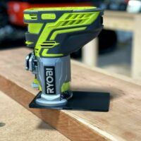 Ryobi trim router with lime-yellow extended base plate mounted on wooden workbench