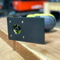 Black extended base plate with circular opening mounted on Ryobi trim router, showing yellow fan wheel visible through port