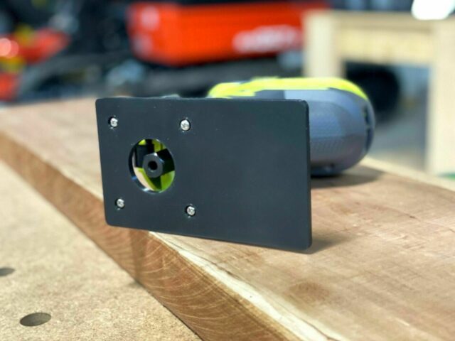 Black extended base plate with circular opening mounted on Ryobi trim router, showing yellow fan wheel visible through port