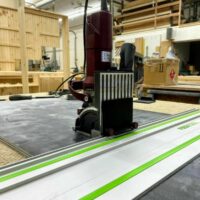 ZetaRail connector mounted on Lamello Zeta biscuit jointer, positioned on Festool guide rail with green stripe in woodworking shop