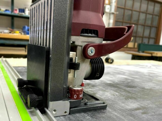 ZetaRail connector mounted on Lamello Zeta with red lever handle and knurled adjustment knob, attached to bright yellow guide rail