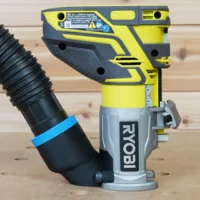 Yellow and gray hose adapter attached to a Ryobi trim router with black corrugated hose connected to the adapter port