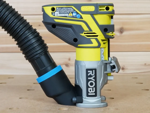 Yellow and gray hose adapter attached to a Ryobi trim router with black corrugated hose connected to the adapter port