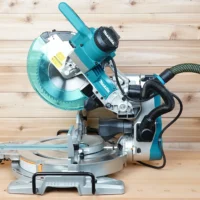 Makita LS/XLS sliding miter saw with a black hose adapter on the dust port linking a green extractor hose