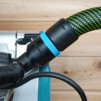 Black ToolCurve 36mm hose adapter with blue ring joining a green dust hose to a Makita miter saw port