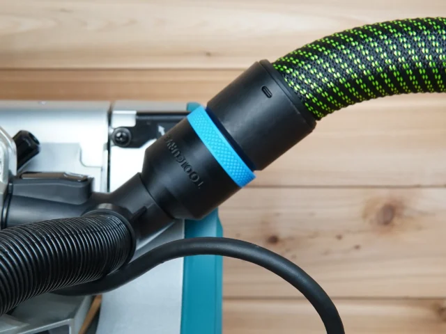 Black ToolCurve 36mm hose adapter with blue ring joining a green dust hose to a Makita miter saw port
