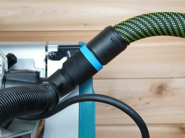 Black hose adapter with blue band attached to Makita miter saw dust port, connected to green and black hose