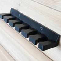 Blue quick clamp wall mount rack with six individual slots holding black clamp heads, mounted on white wood paneling