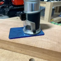 Blue transparent acrylic base plate mounted on a Makita trim router sitting on a wooden workbench