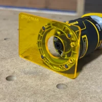 Yellow acrylic base plate attached to a Dewalt trim router, showing mounting holes and extended cutting surface
