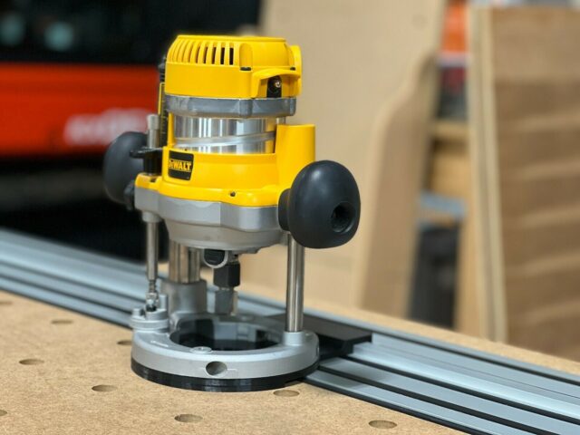 DeWalt DW618 plunge router mounted on DeWalt track saw rail, showing adapter base and router positioned for routing along the track