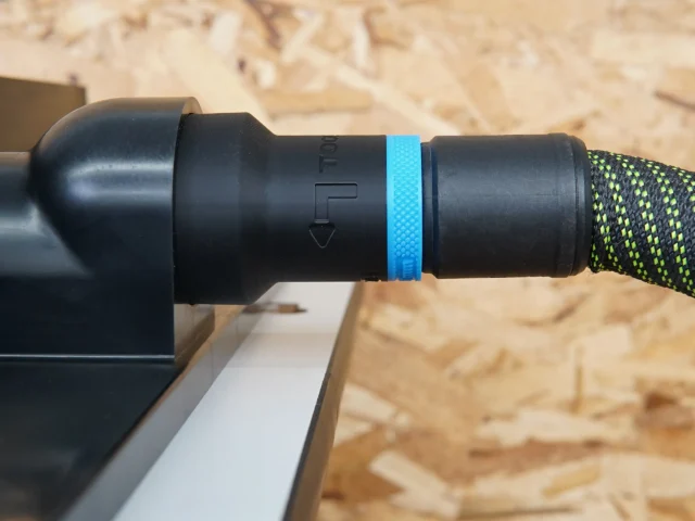 Black hose adapter with blue band attached to router table dust port, connected to green and black hose