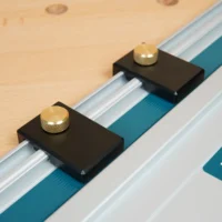 Two black aluminum guide rail limit stops with brass knurled knobs mounted on Makita track saw rails