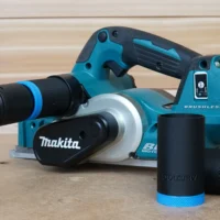 Black ToolCurve hose adapter with blue ring fitted to a Makita cordless planer dust port, two spare adapters beside it