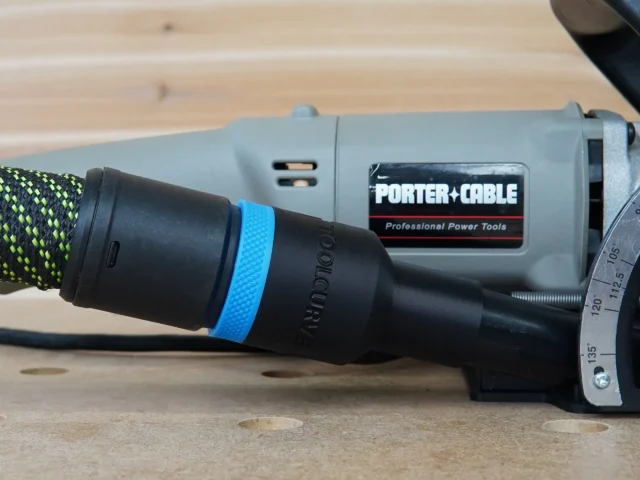 Black hose adapter with blue band attached to Porter Cable plate joiner 557, connected to braided green hose