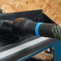 Black hose adapter with blue ring joining a green-flecked extractor hose to a router table dust port