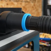 Blue hose adapter with threaded ports mounted on a router table dust collection port